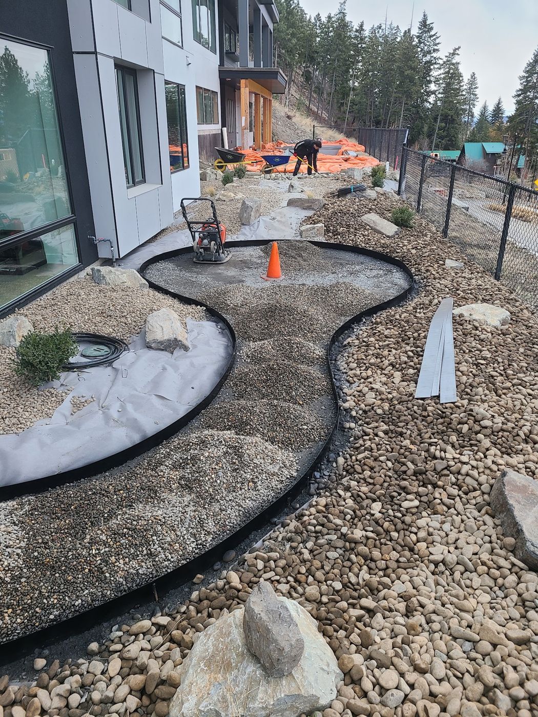 New rock and gravel bed with edging beside a building