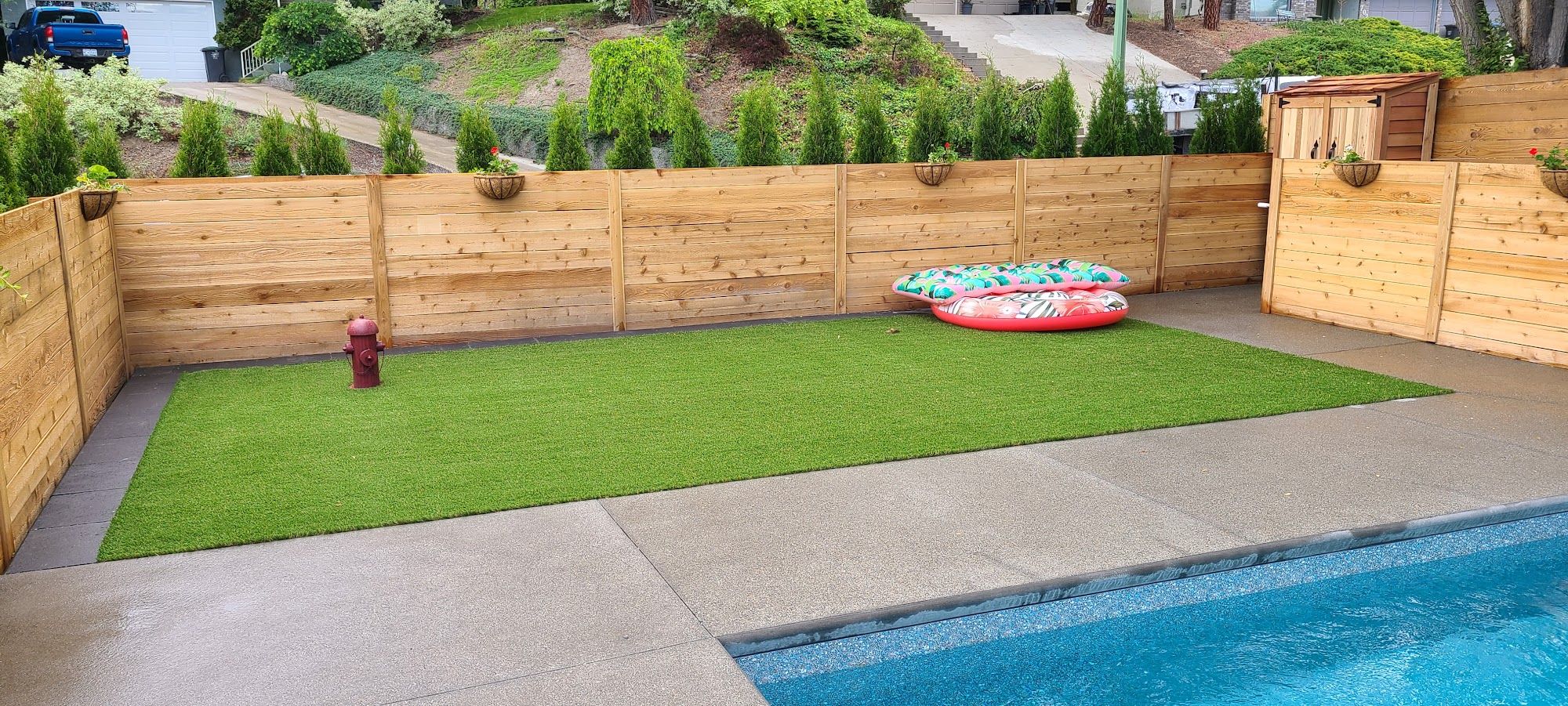 Backyard with green turf and cedar fence beside a pool